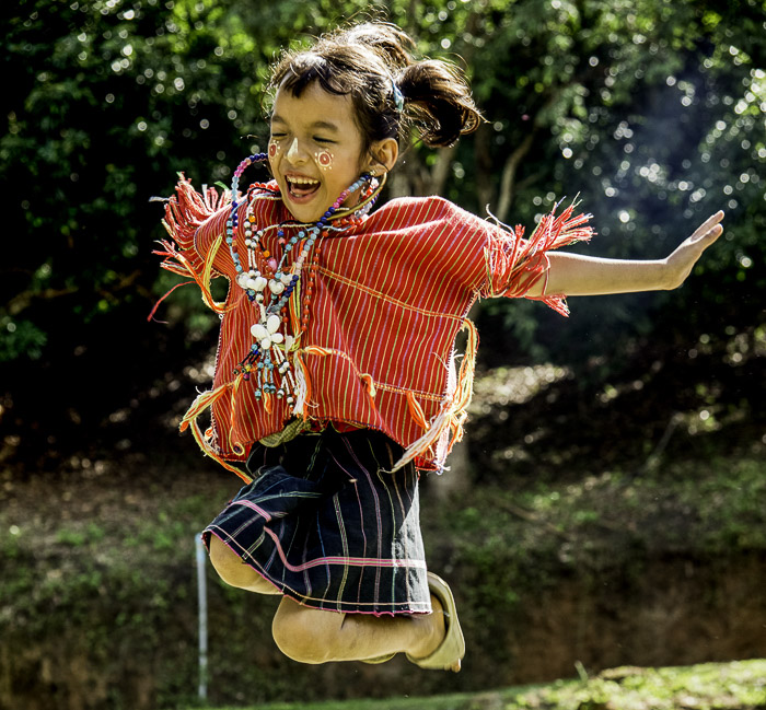 A portrait of a young child jumping with joy, shot using backlight photography