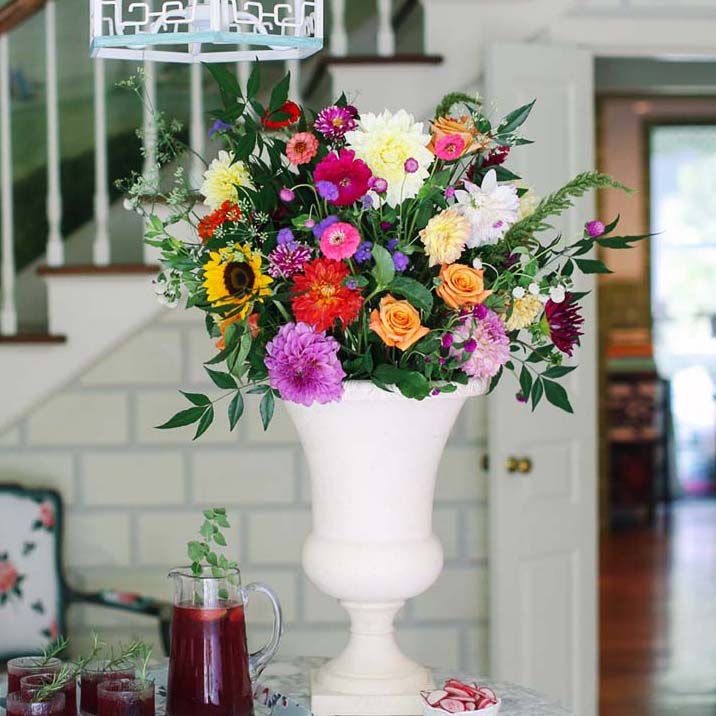 Large zinnia flower arrangement in a white urn