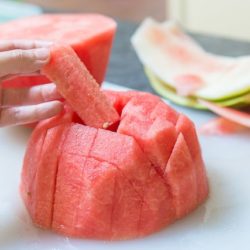 A close up of watermelon sticks on a cutting board