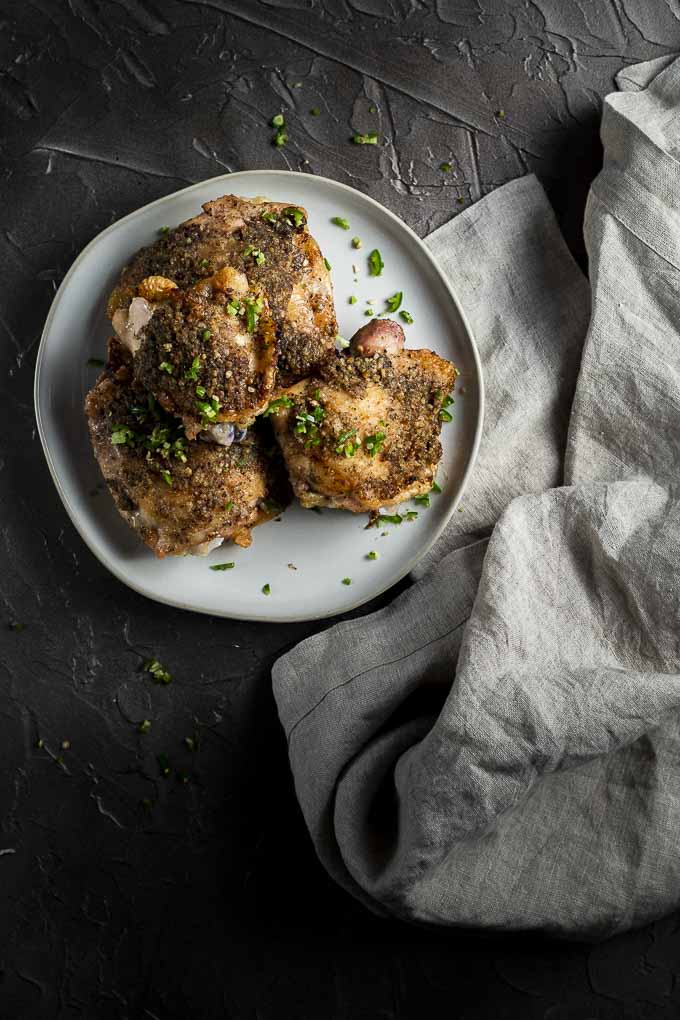 roasted chicken thighs on a plate with diced chilies on top