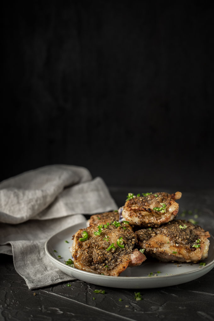 plate of crispy chicken thighs with diced green chilies on top